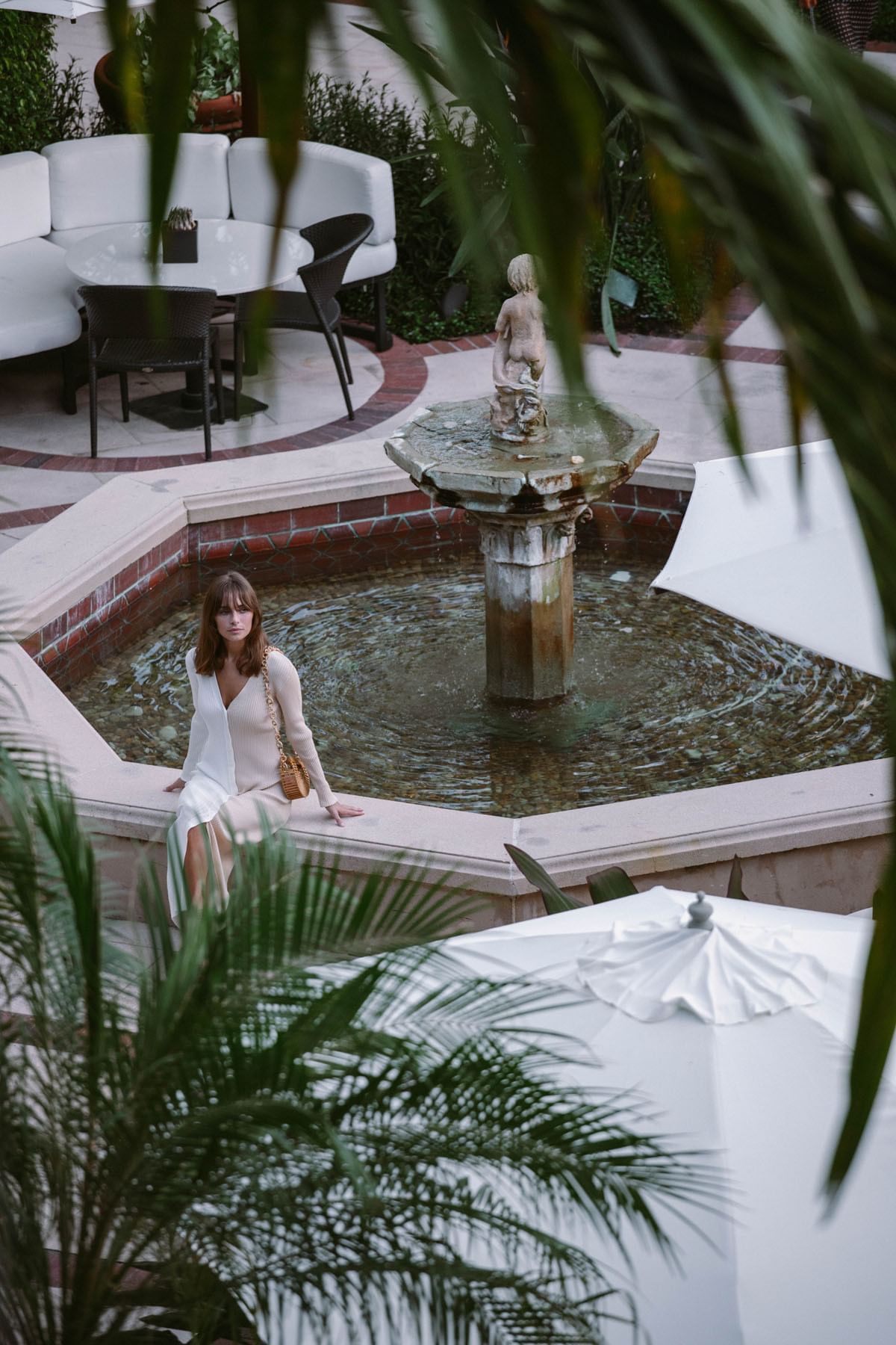 A woman sitting near to fountain at  Brazilian Court